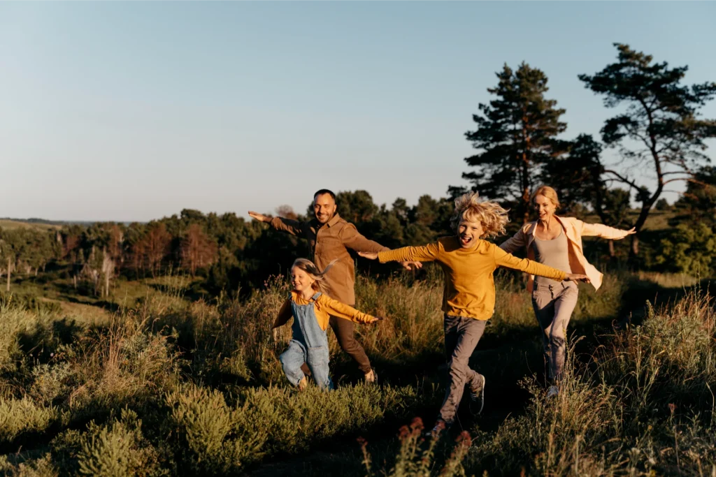 Family running through a sunlit meadow, enjoying an active day outdoors.
